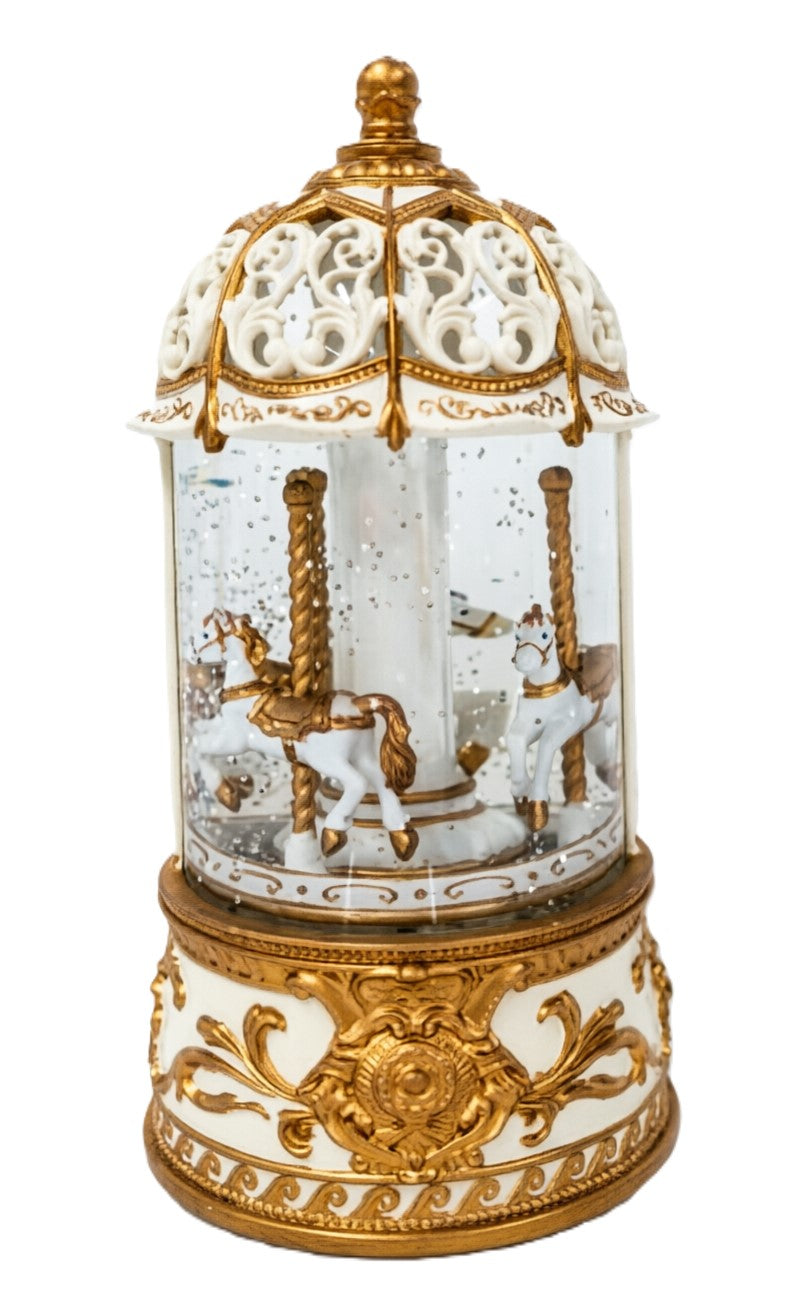 An ornate musical carousel snow globe decoration with a gold-finished, white porcelain details, and a clear glass body showing a small carousel scene inside.