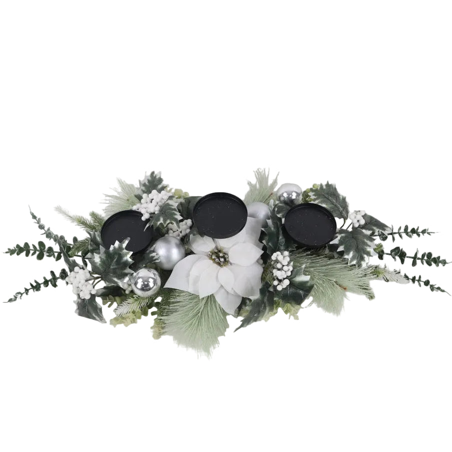 A festive Christmas wreath centerpiece with green pine branches, white poinsettia flowers, silver ornaments, and 3 black candle holders.