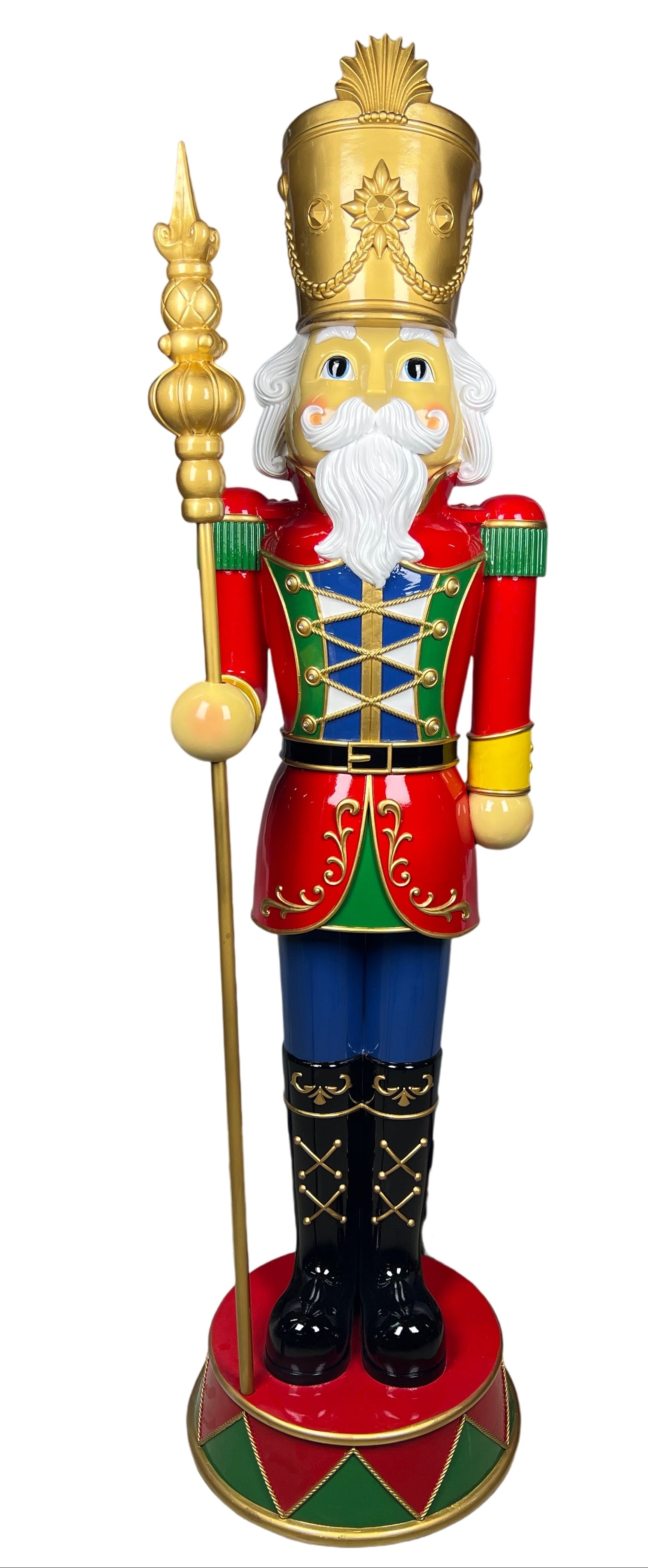 A traditional Christmas nutcracker figurine standing on a round base, wearing a red and green uniform with blue pants, black boots, and a gold crown, holding a gold staff.