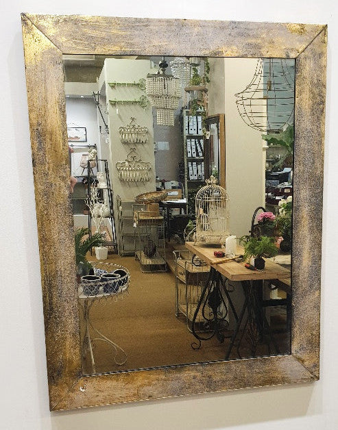 A rectangular metal mirror frame with a textured gold finish