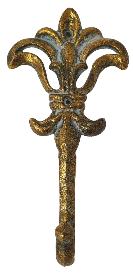 An ornate vintage-style metal wall hook shaped like a fleur-de-lis, finished in a distressed gold and antique brass look