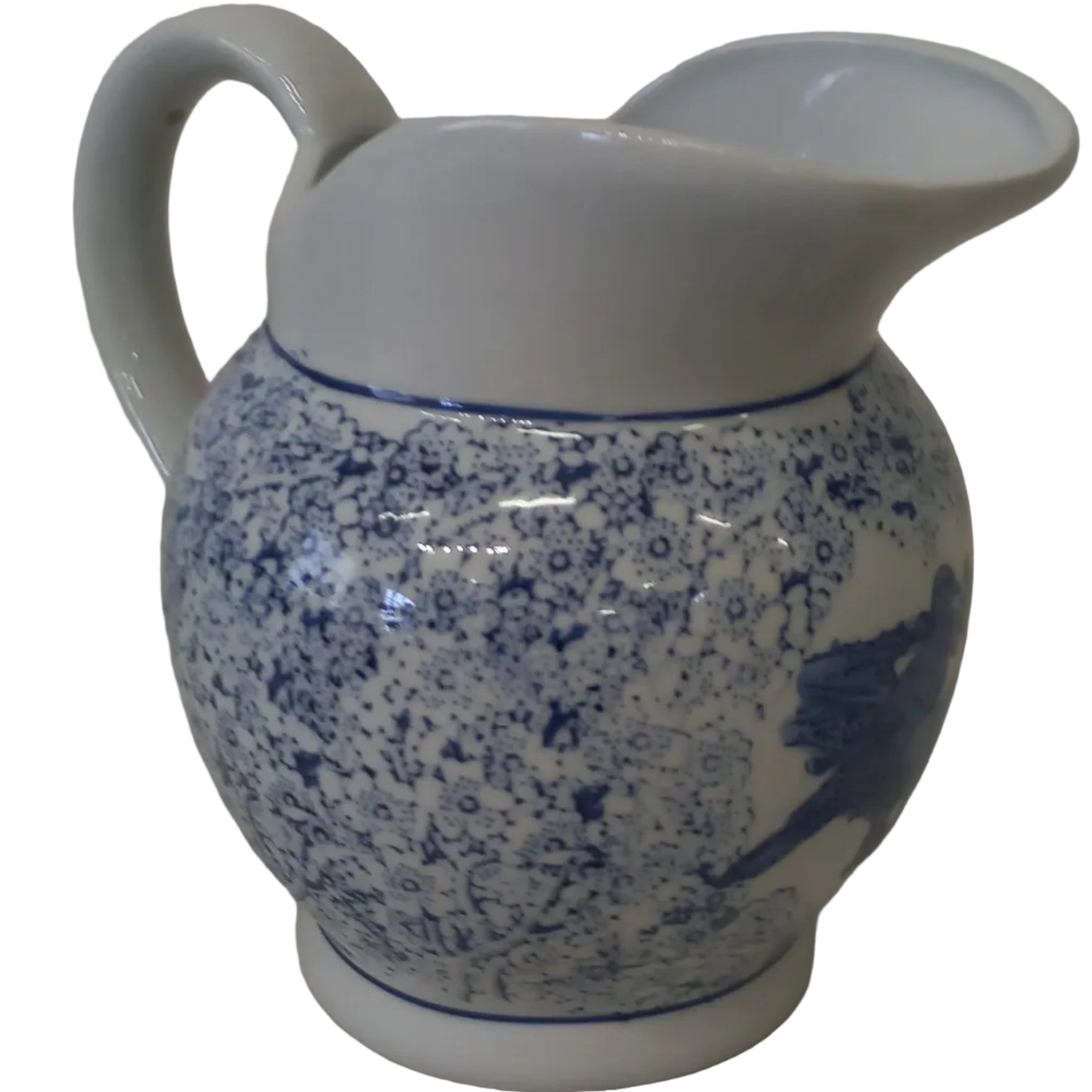 A white ceramic pitcher with blue floral patterns and a handle