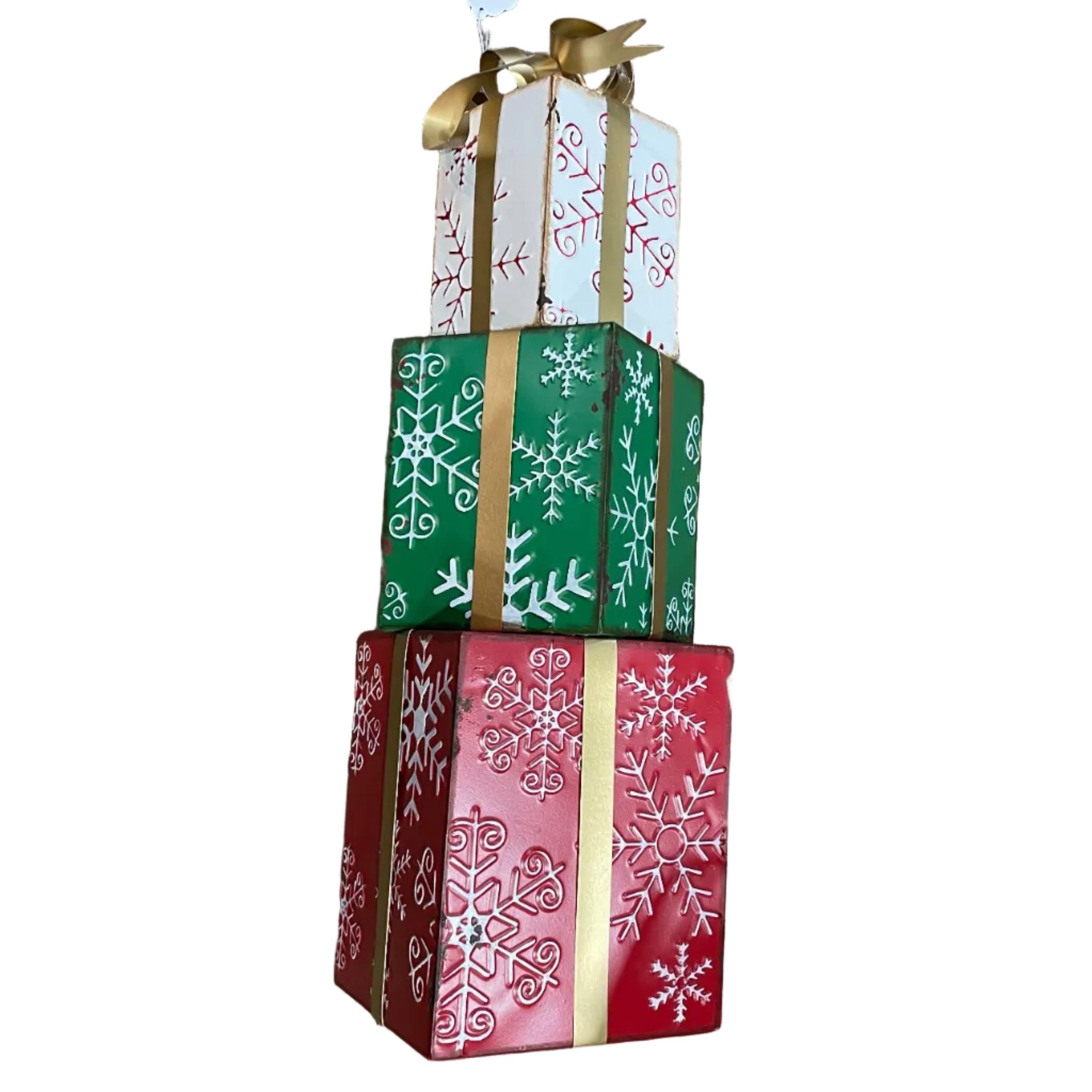 A decorative metal stacked gift box arrangement with three tiers of wrapped boxes in white, green, and red, each printed with snowflake patterns and tied together with a gold ribbon.
