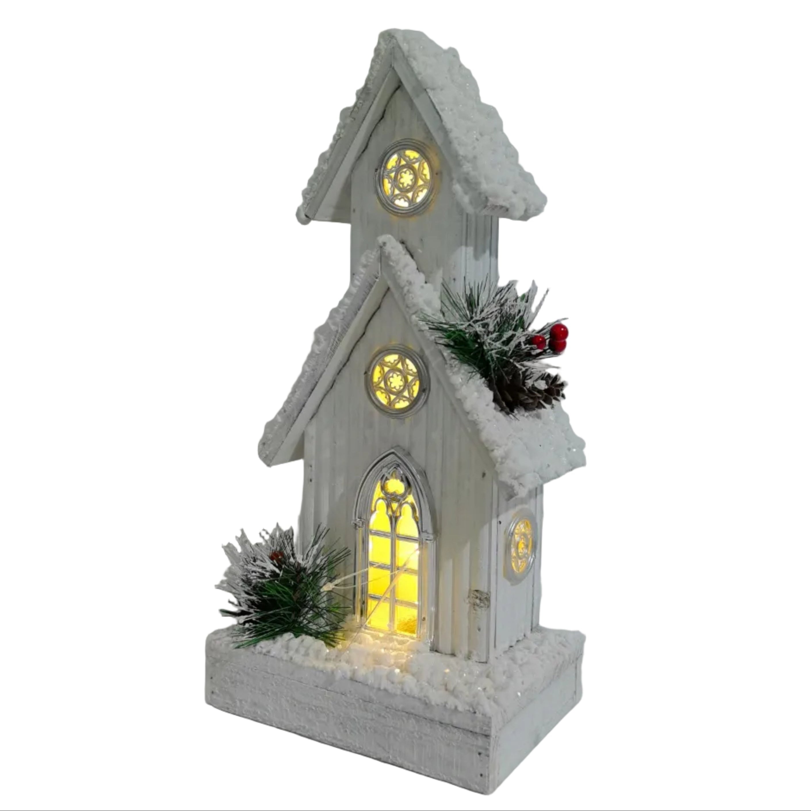 A small white wooden Christmas Chapel ornament with a warm yellow glowing window, faux snow on the roof and base, small green pine branches, and a tiny red berry accent.