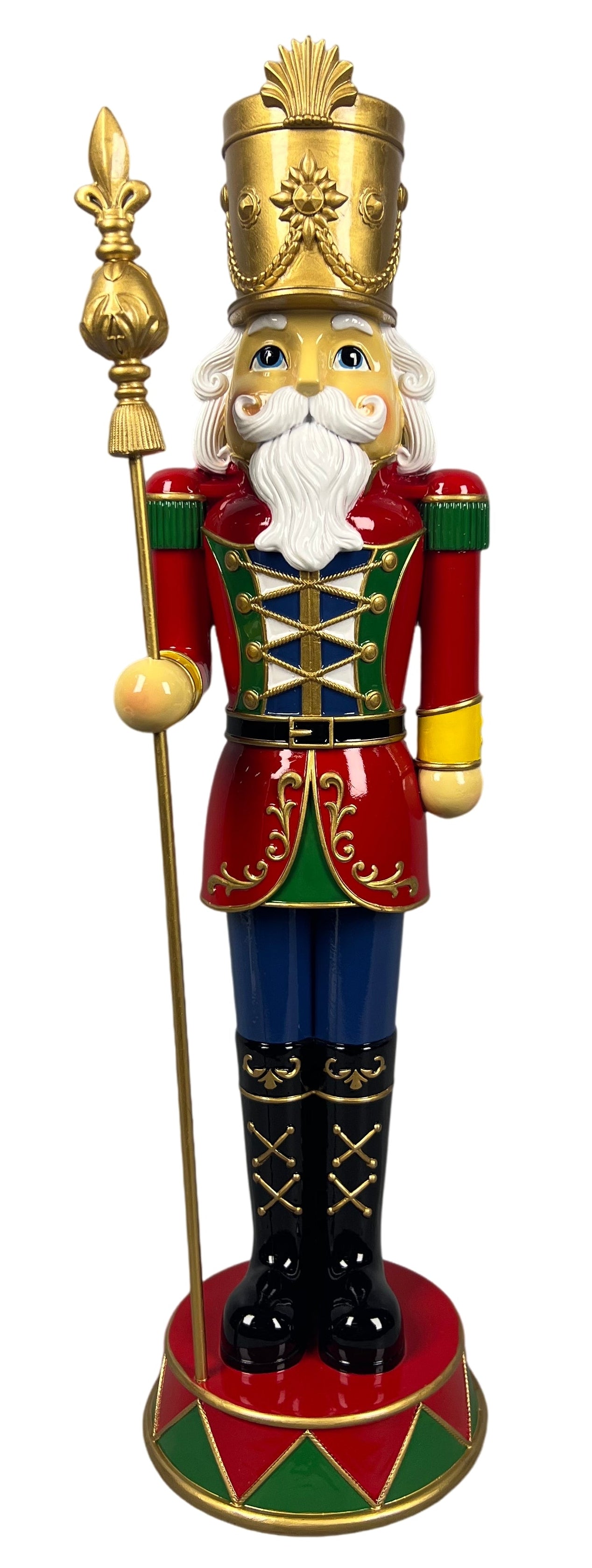 A traditional Christmas nutcracker figurine standing on a decorated base, holding a gold spear. The nutcracker features a red coat with green and gold trim, blue pants, black boots, and a tall gold hat.