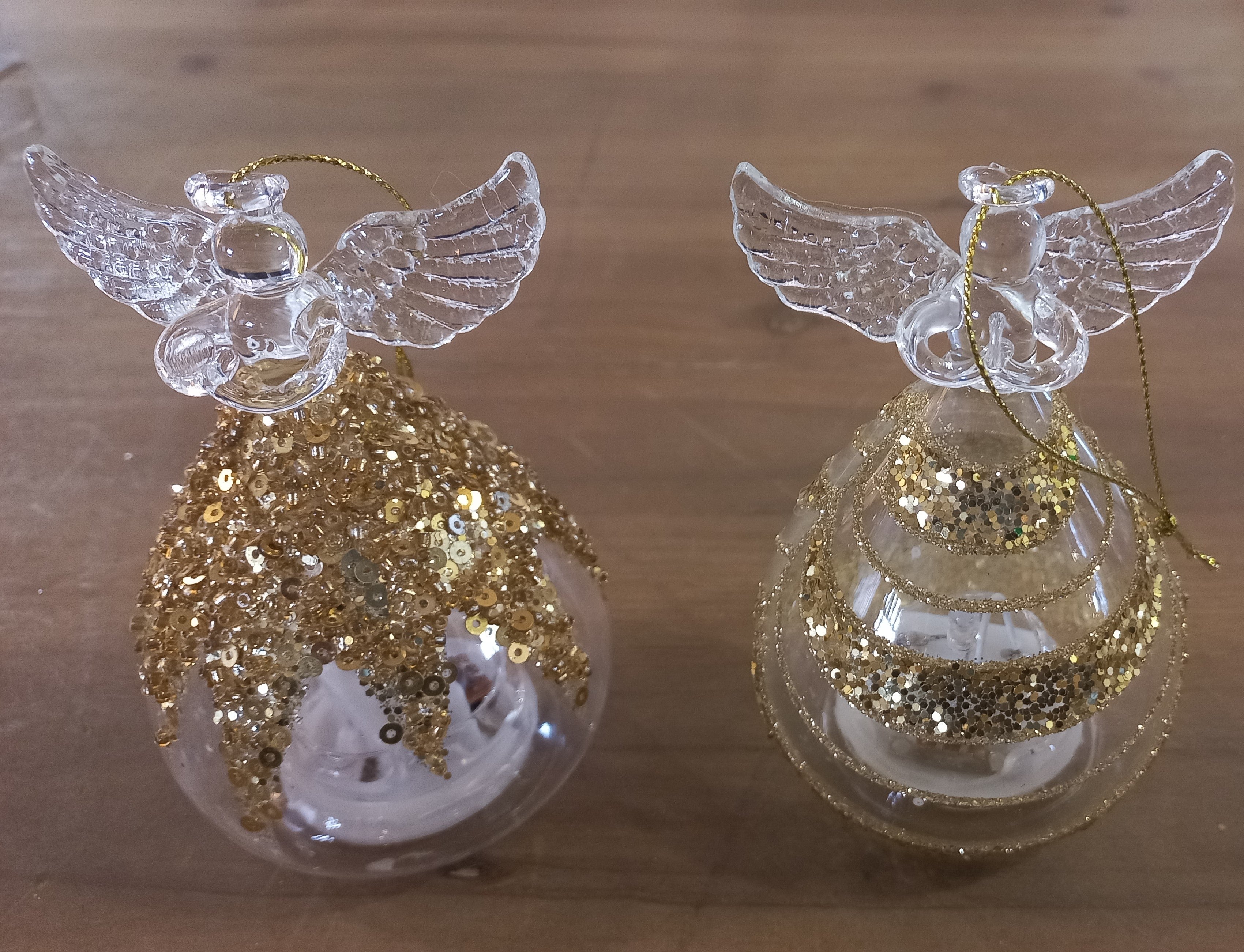 Two glass ornaments, each featuring a gold crusted angel figure with wings outstretched.