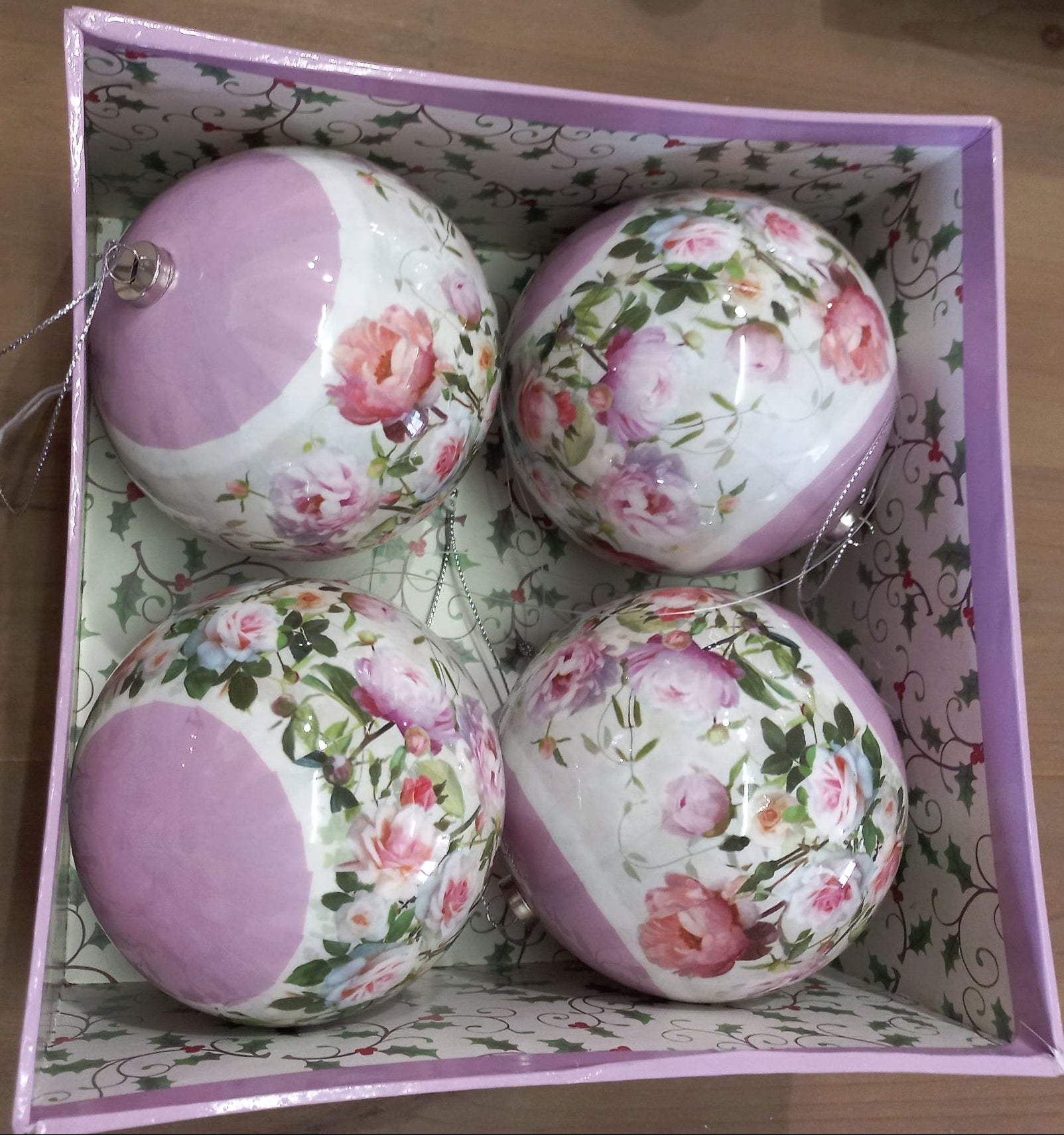 A set of four pink and white floral patterned paper hanging Christmas balls in a decorative box.